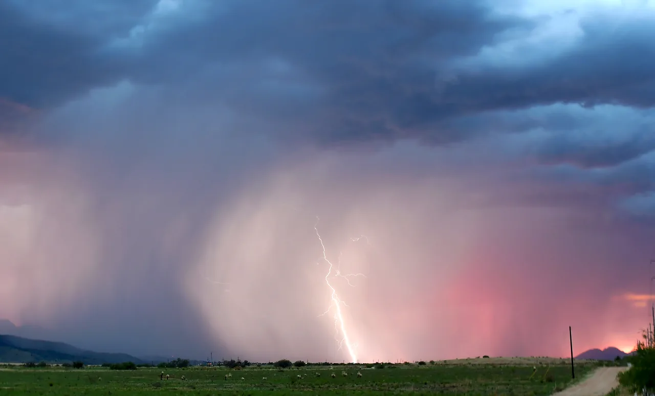 Lightning and a curtain of rain beneath a monsoon thunderstorm in southern Arizona.