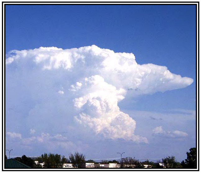 Real cumulonimbus tower and spreading anvil over buildings, photographed and reproduced in the FAA cloud atlas.